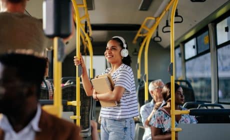 femail Student thats on a bus moving to a new city, wearing headphones and smiling